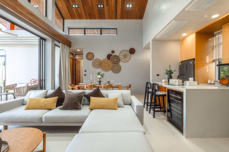 An open-concept living area with a high vaulted ceiling and views of a lush tropical garden.