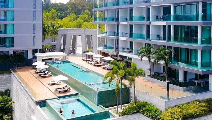 A balcony offers a panoramic view of an ocean and distant coastline under a partly cloudy sky.