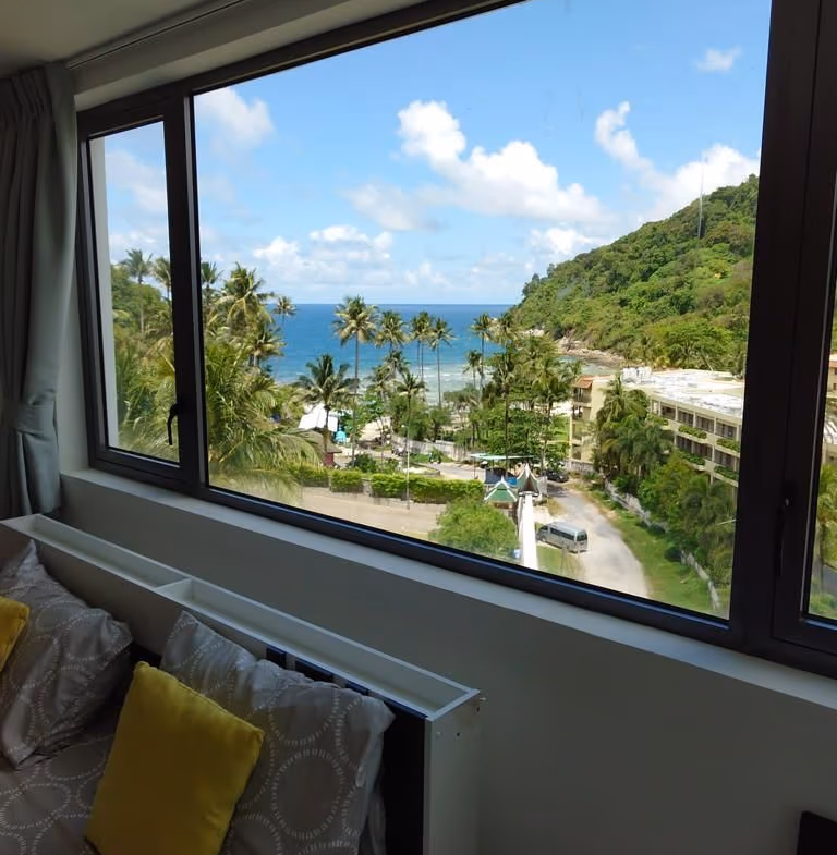 A private swimming pool overlooks the ocean and surrounding hills from a balcony.