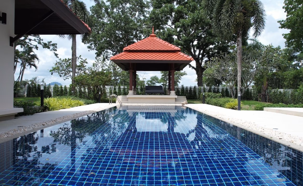 Exterior view of a three-bedroom hotel in Phuket, featuring a private pool and a golf course in the background.