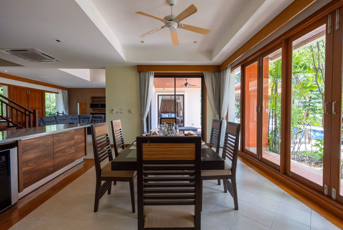A spacious, modern living room with large windows overlooking a swimming pool and the ocean.
