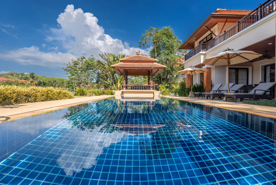 Exterior of a 4-bedroom villa in Laguna, featuring a private pool. The villa has a modern design with large windows and a manicured lawn.