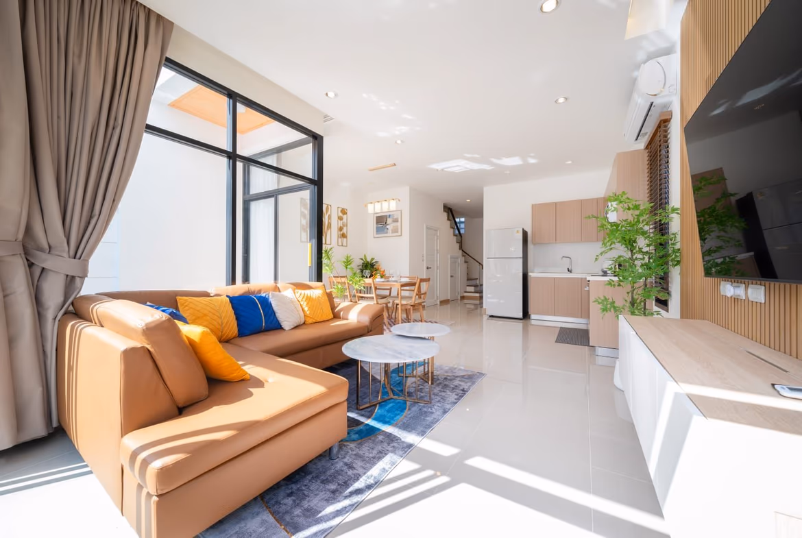 A bedroom with a large window overlooking the pool and tropical vegetation.