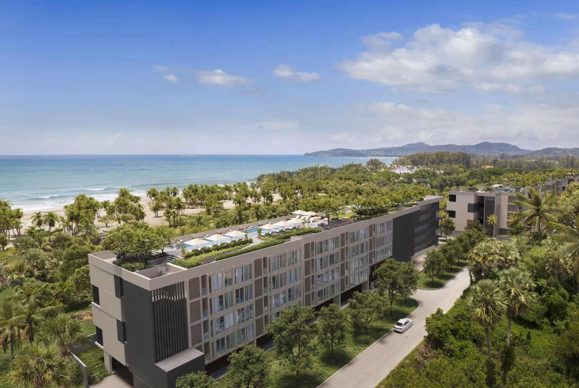 Exterior view of a three-bedroom condominium unit within a gated community in Bang Tao, Thailand. The building features multiple balconies and a modern facade.