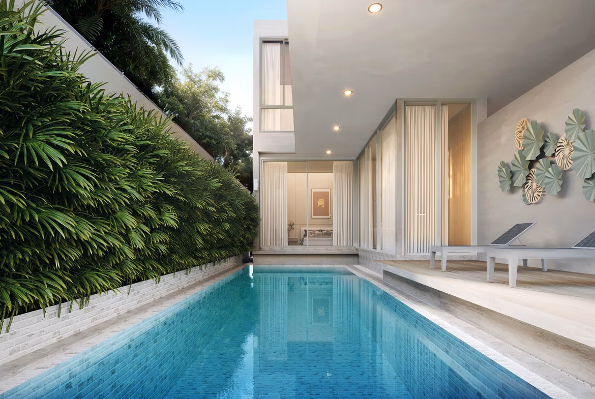 A modern, minimalist living room with a large sofa and flat-screen TV opens onto an outdoor patio with a swimming pool.