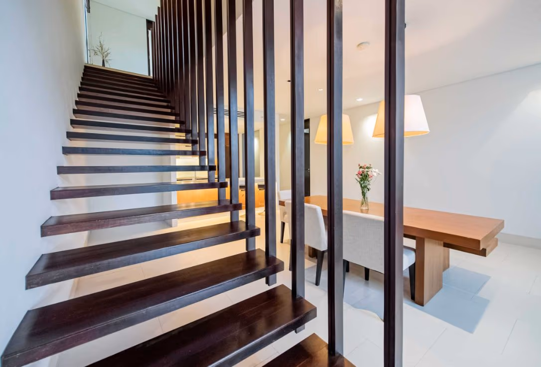 A spacious, modern living room with large windows leading to an outdoor patio with a pool.