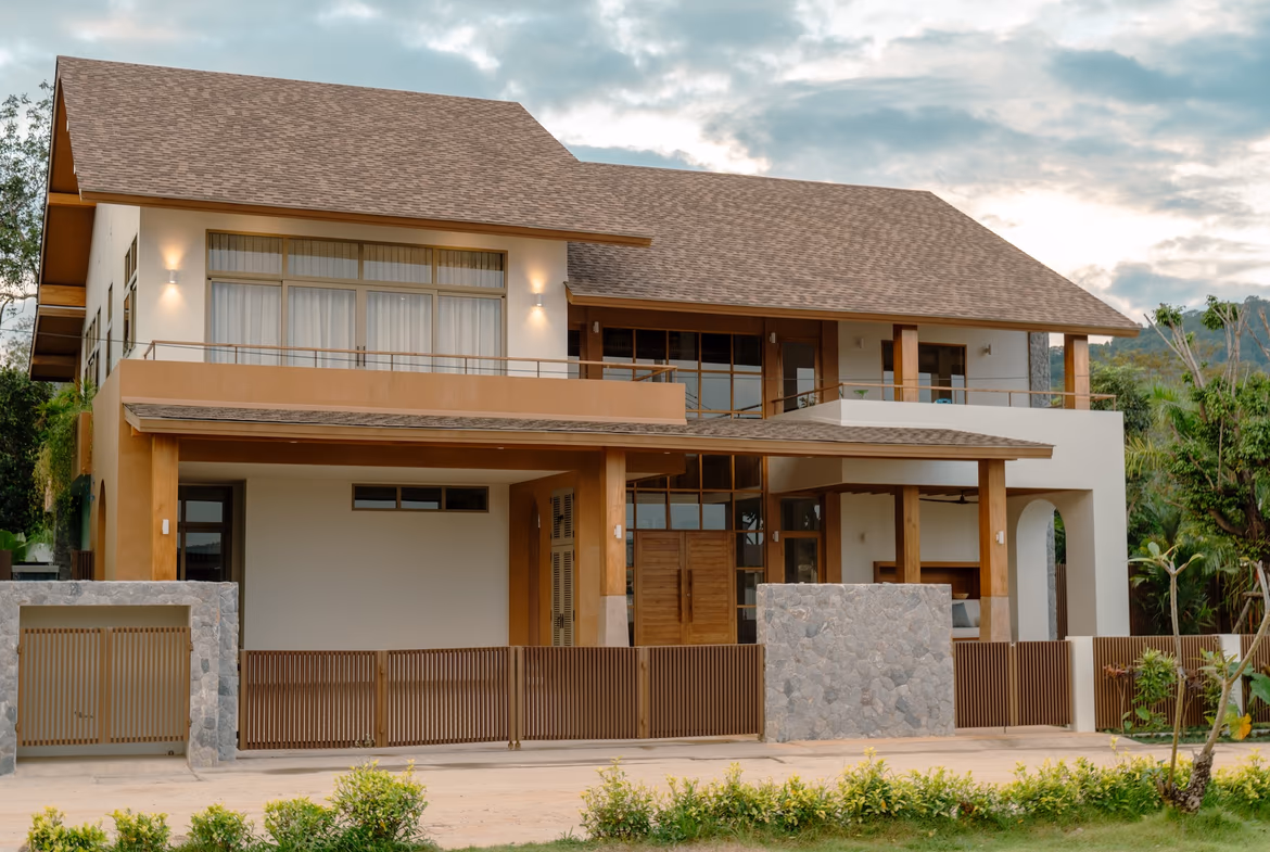 A modern four-bedroom villa in Cherngtalay features a flat roof and a swimming pool surrounded by lush greenery. The property is nestled in a green valley.