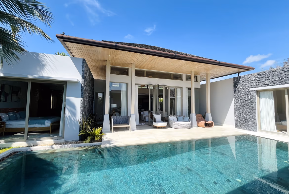 A tropical outdoor pool area with loungers and lush greenery.