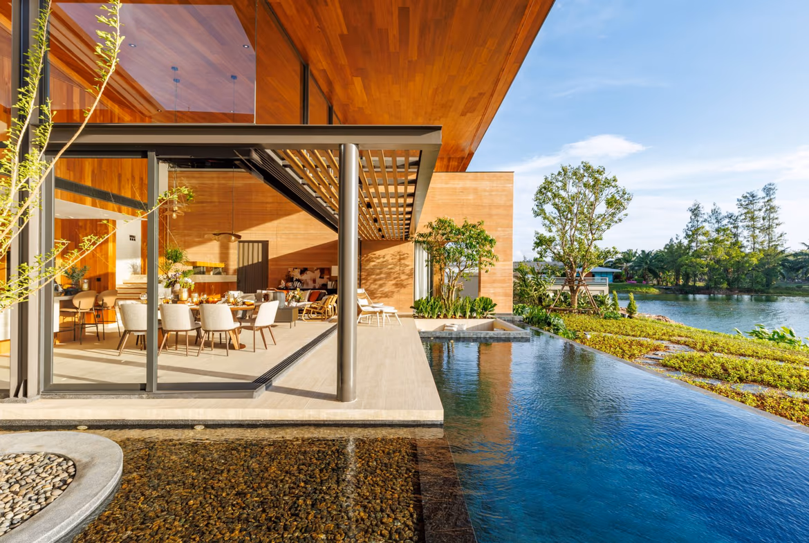 An infinity pool overlooks a lake with lush mountains in the background.