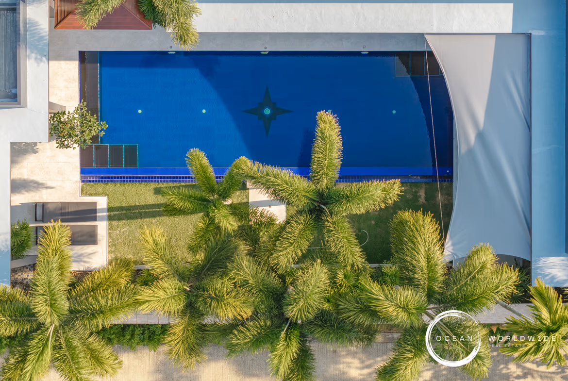 A bedroom with a large bed and a balcony overlooking a pool.