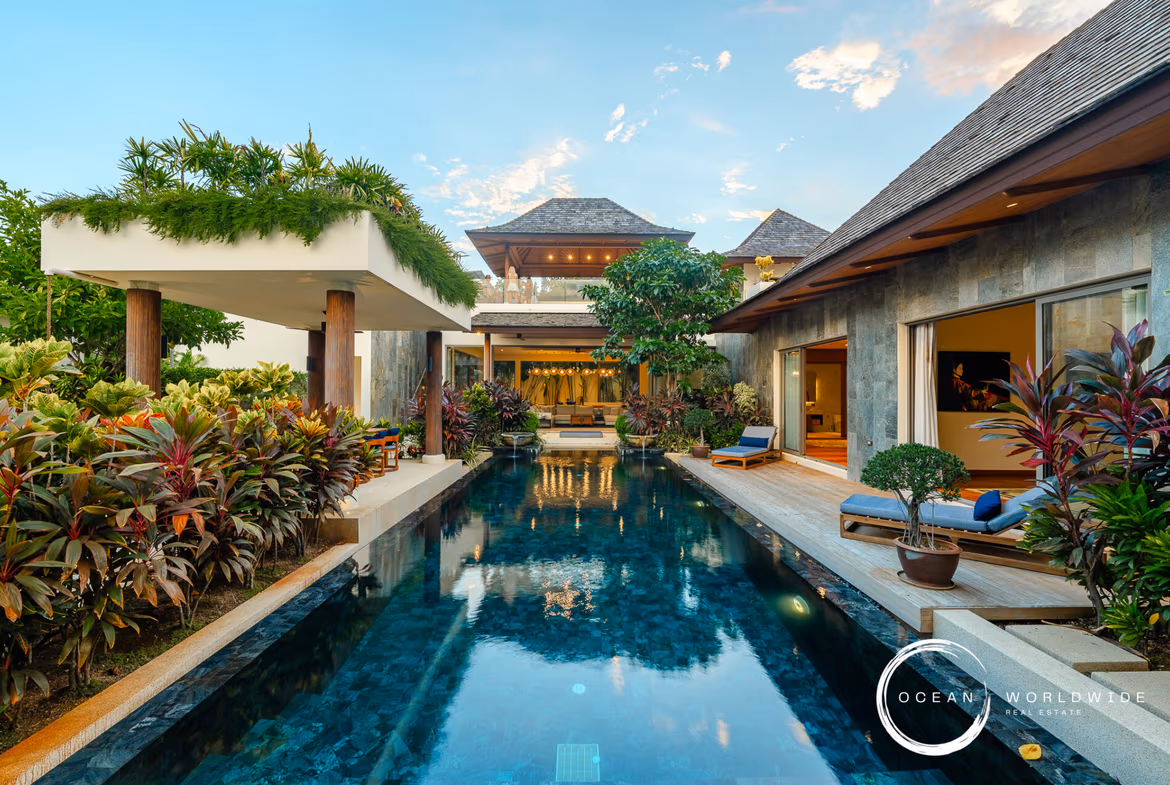 Luxurious resort pool courtyard with tropical plants, lounge chairs, and open-air seating areas.