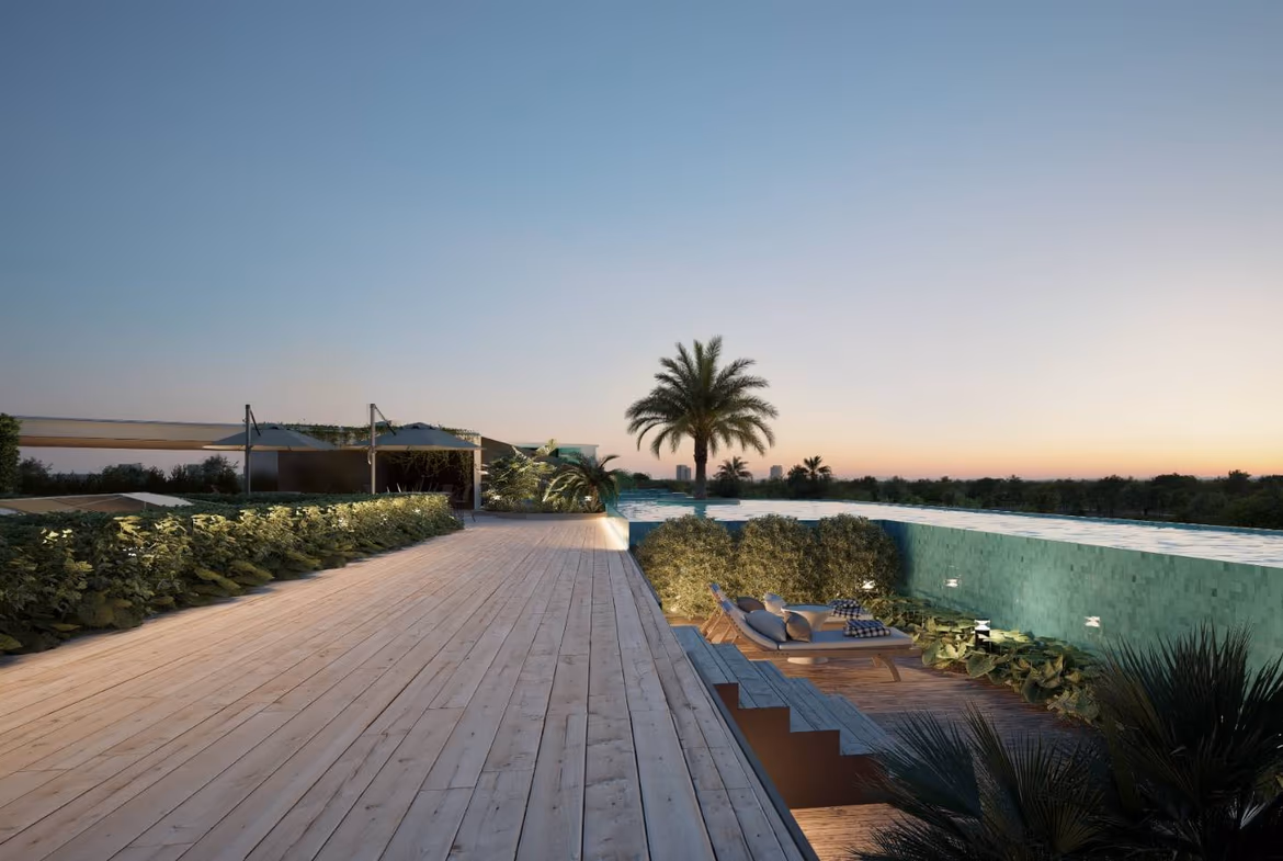 Sunset view over a luxurious rooftop pool area with palm trees, a wooden deck, and lounge chairs.