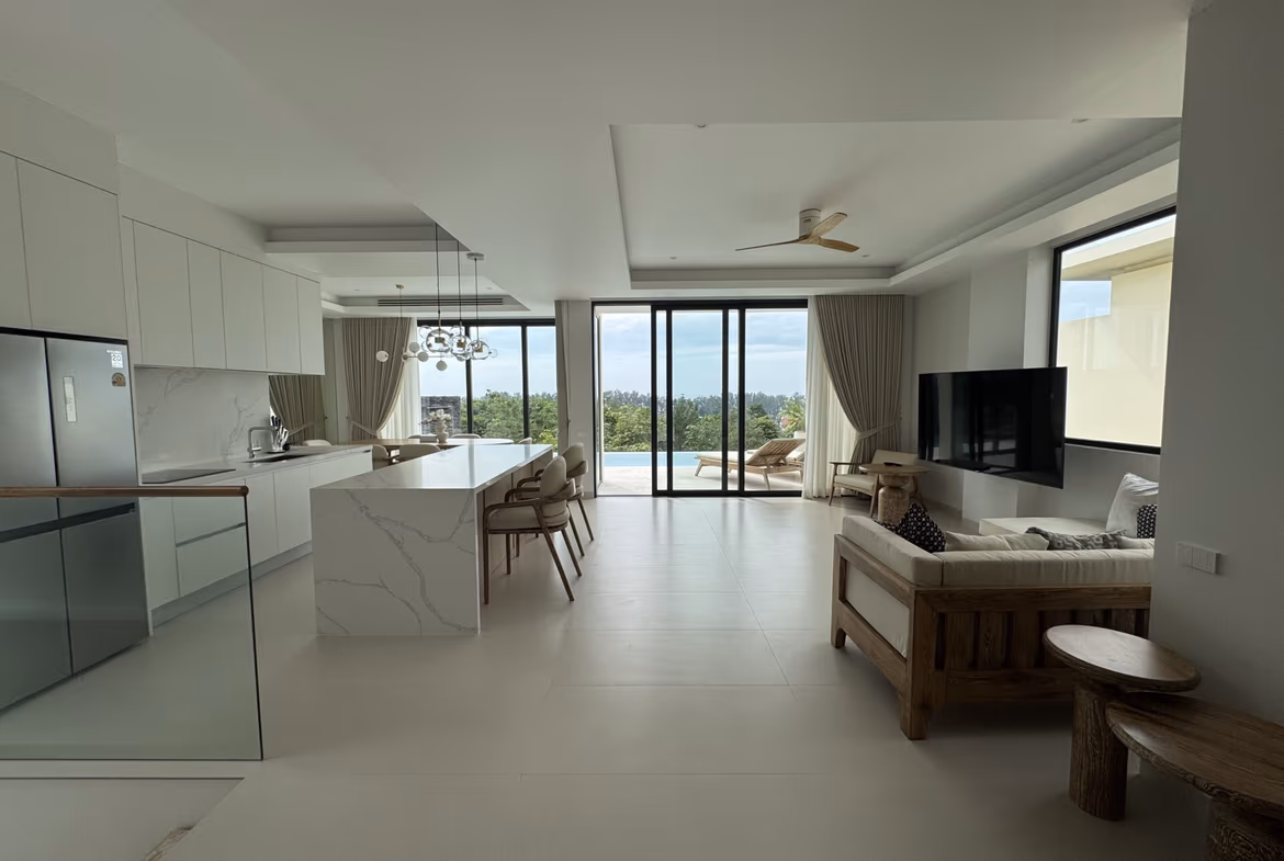 Open-concept kitchen and living area with white cabinets, marble island, and a seating area, large glass doors to a balcony with a pool view outside