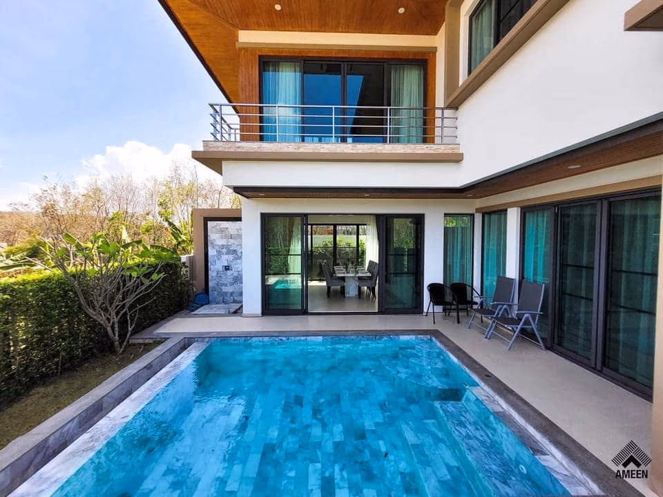 Modern two-story home with a rectangular pool, glass doors, and outdoor seating on a sunny backyard patio